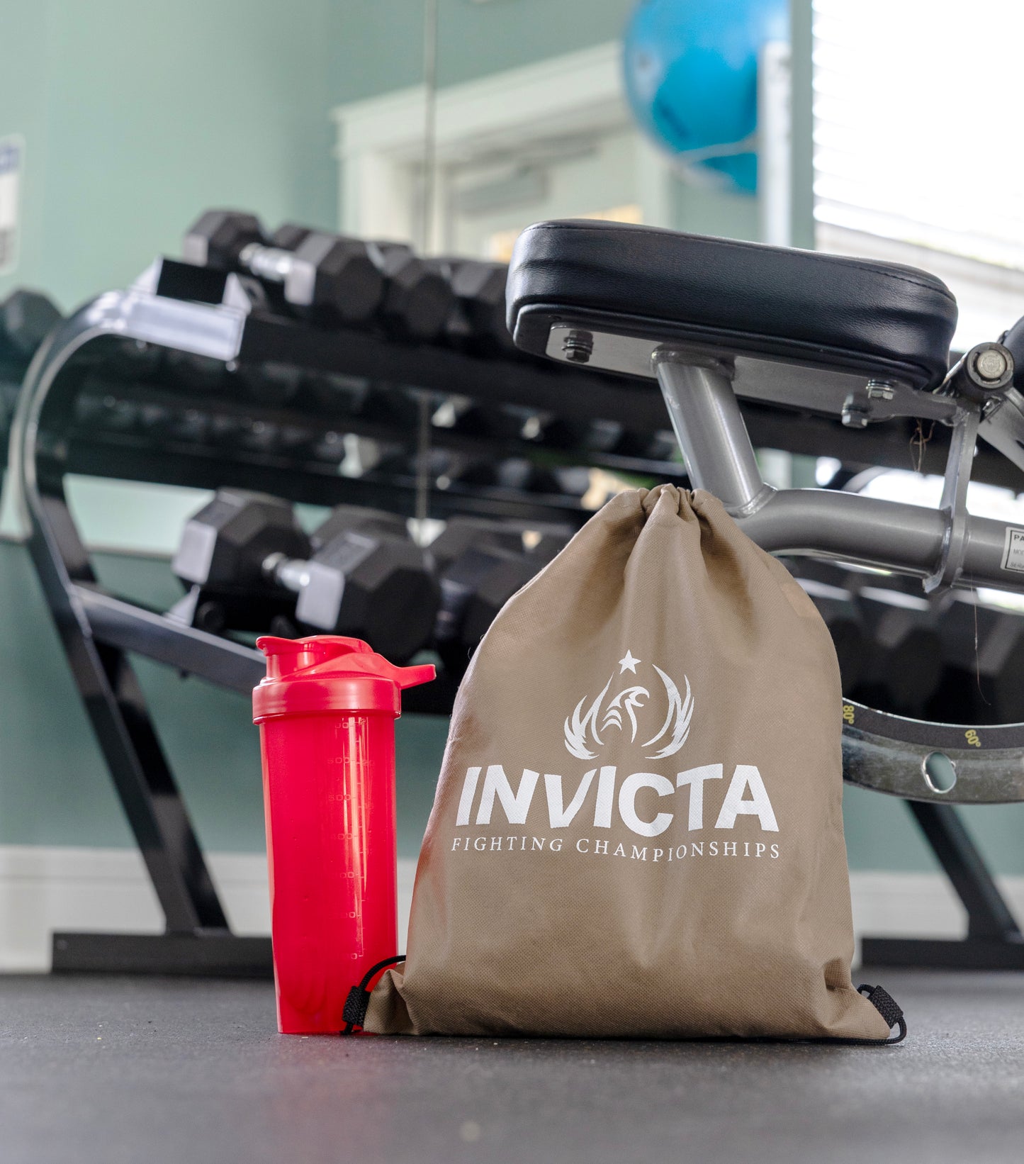 Blue Invicta FC bag next to a shaker bottle inside a gym